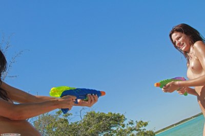 Twee naakte vriendinnen spelen met waterpistool