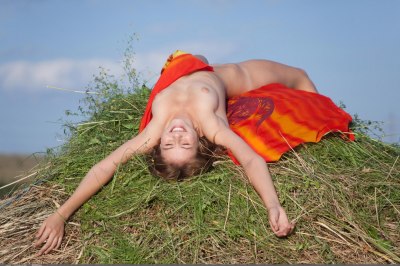 Schoolmeisje naakt in een berg met hooi