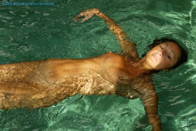 Gespierd en slank meisje zwemt naakt in binnenzwembad