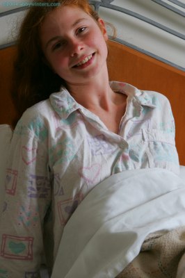 Meisje in bed doet haar pyjama uit en laat haar mooie tienerborstjes zien