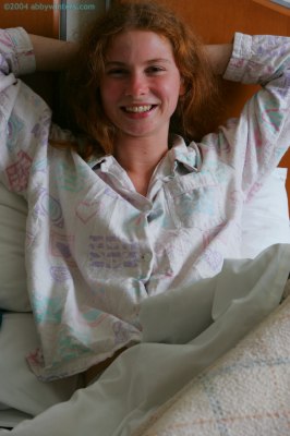 Meisje in bed doet haar pyjama uit en laat haar mooie tienerborstjes zien