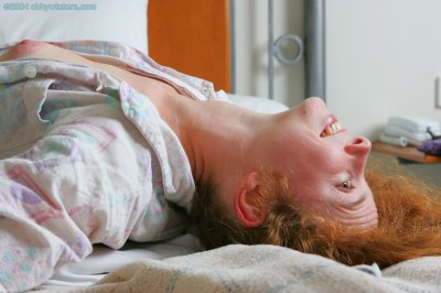 Meisje in bed doet haar pyjama uit en laat haar mooie tienerborstjes zien