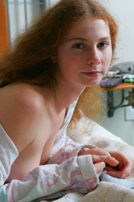 Meisje in bed doet haar pyjama uit en laat haar mooie tienerborstjes zien