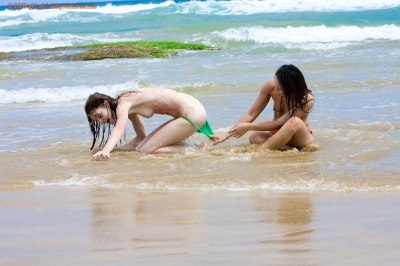 Meisjes spelen bloot met elkaar op het strand