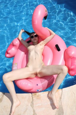 Blote meid op een flamingo zwemband